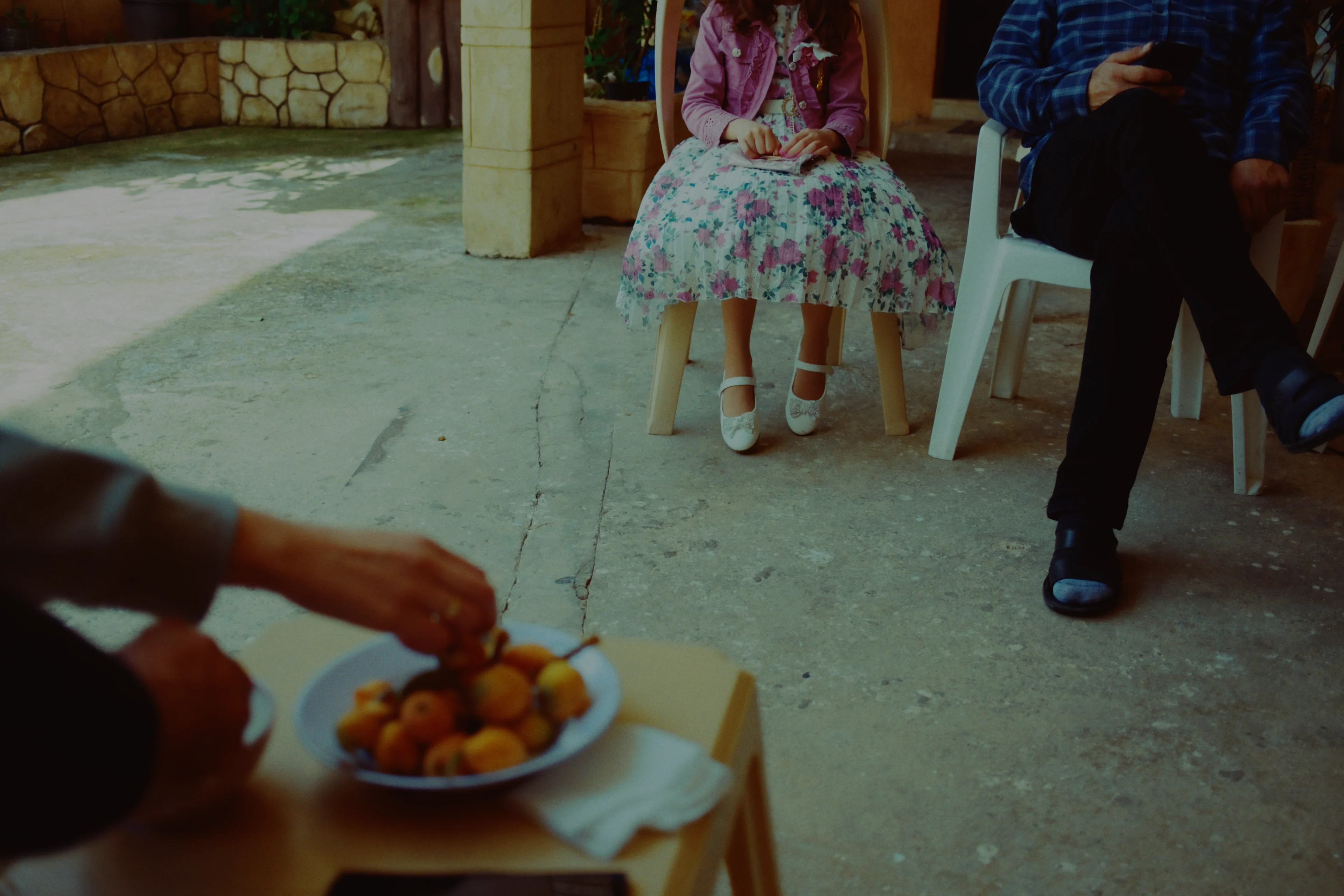 A family gathered in a stone courtyard, a bowl of loquats in the foreground, developed on ColorPlus 200