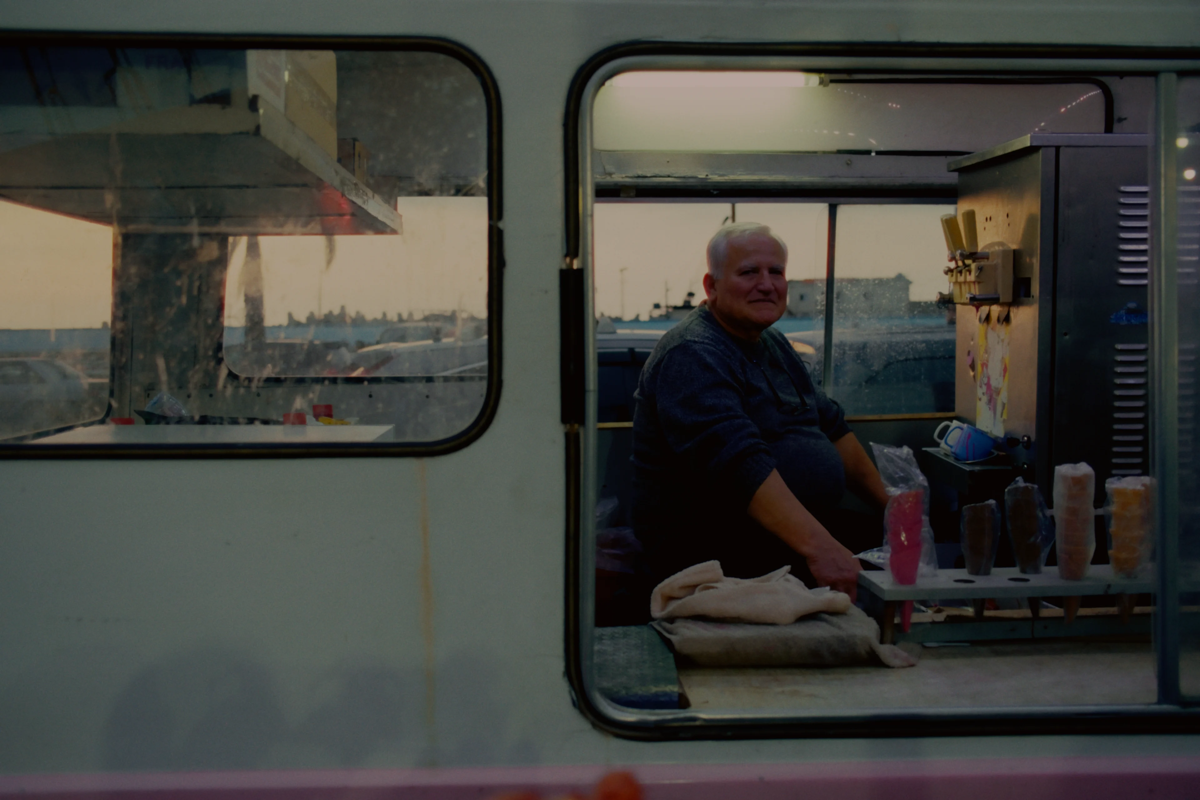 An ice cream vendor seen through the window of his truck at dusk, developed on Vision3 200T